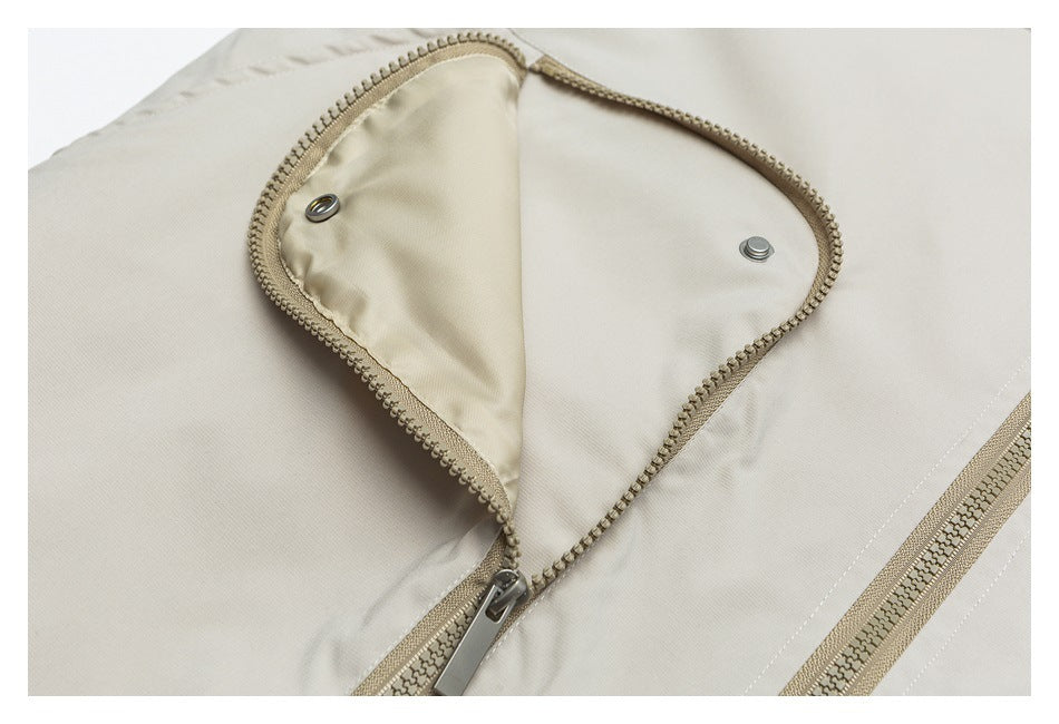 Close-up of an opened zippered pocket flap with metal snaps on a light beige garment.