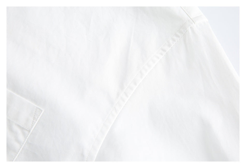 Close-up of a white shirt showing a diagonal seam and a small edge of a pocket.
