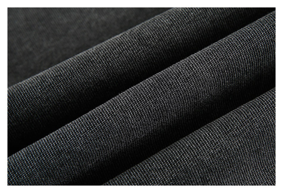 Macro view of dark charcoal fabric gathered into folds, showing its fine knit texture.
