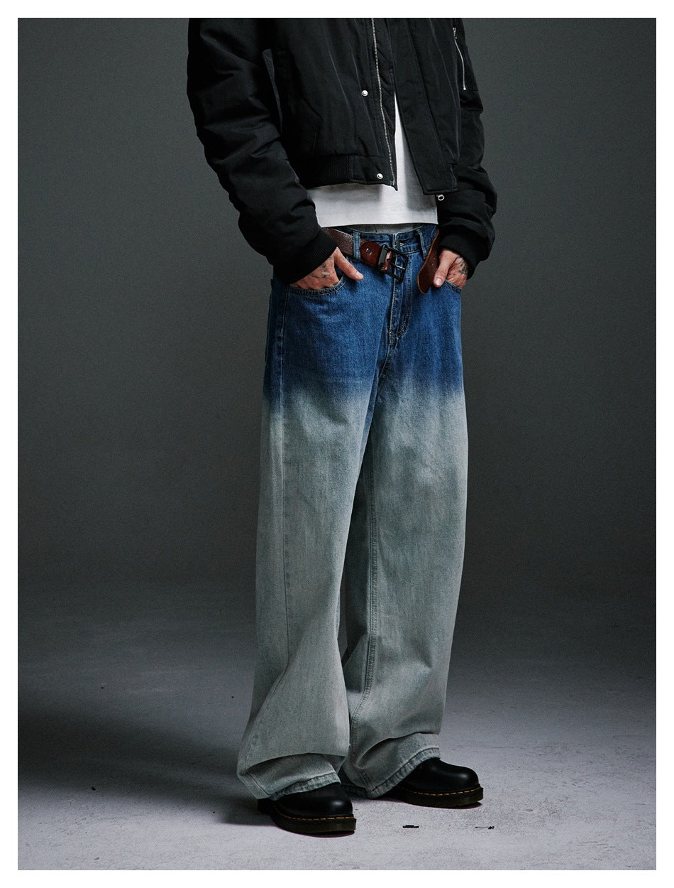 Person wearing gradient wash wide-leg jeans with a brown belt, white tee, black jacket and black boots, cropped at torso