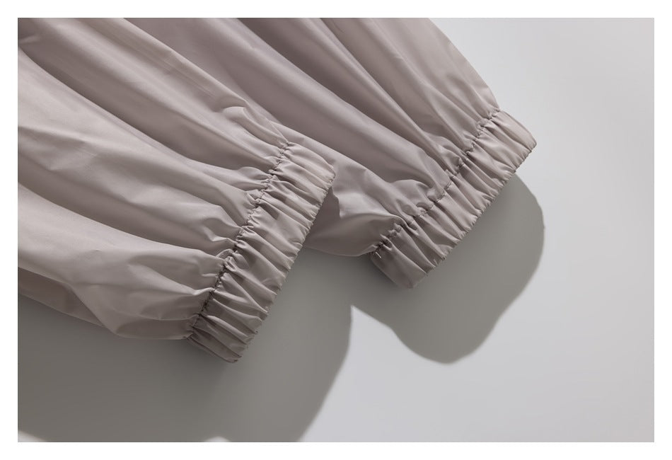 Close-up of gathered elastic cuffs on the sleeves of a light taupe jacket.