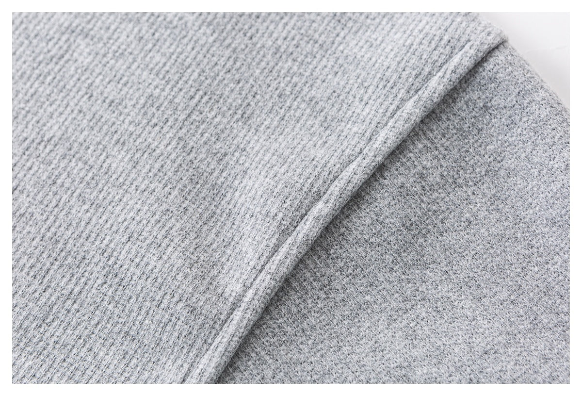 Close-up of a stitched seam joining two areas of light gray textured fabric.