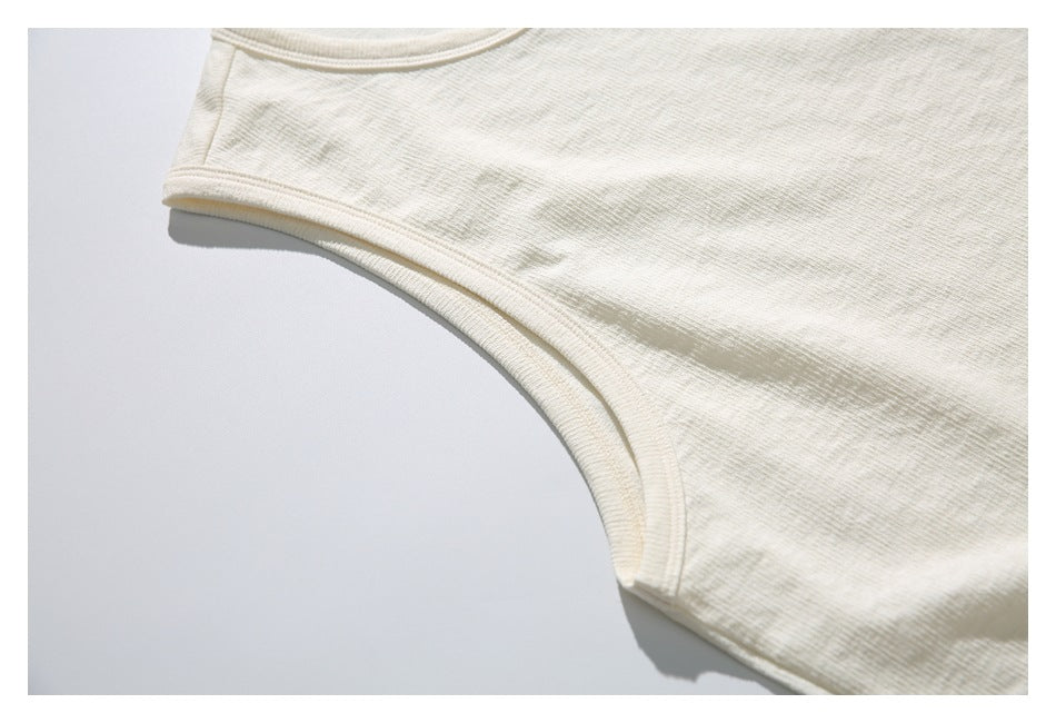 Close-up of the ivory top's bound armhole and shoulder seam, laid flat.