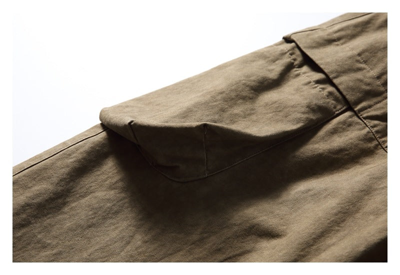 Close-up of an olive-brown flap pocket on the pants, with stitched seams.