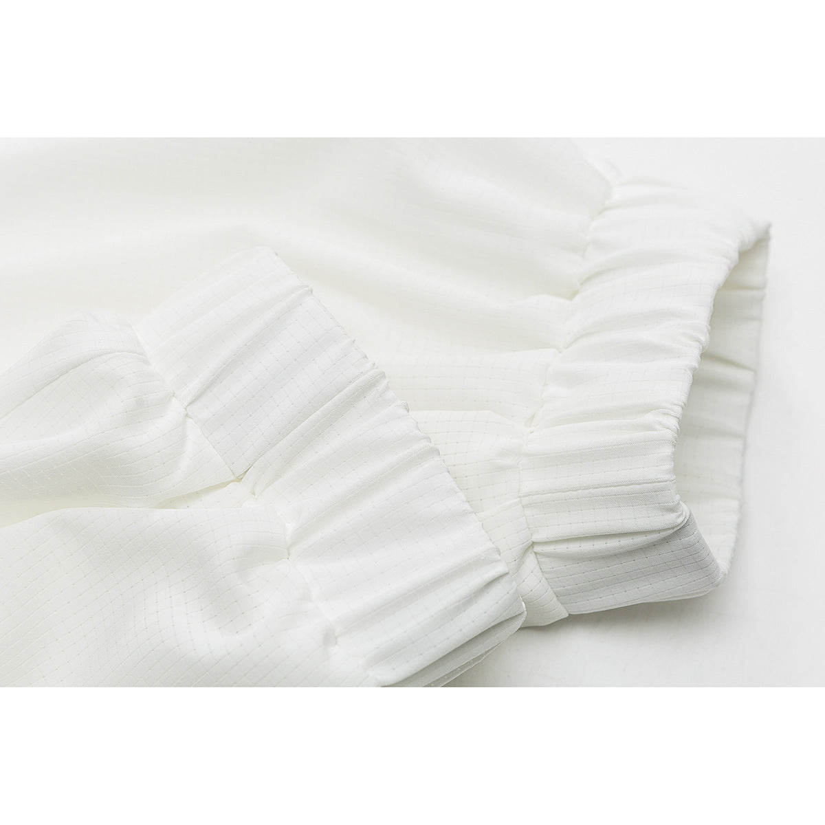 Close-up of the white jacket's gathered elastic sleeve cuffs and stitched panels.