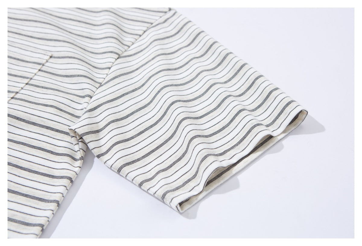 Close-up of the short sleeve and cuff of an ivory shirt with thin dark stripes.