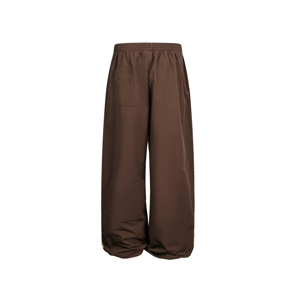 Back view of brown wide-leg trousers with an elastic waist and a rectangular patch pocket.