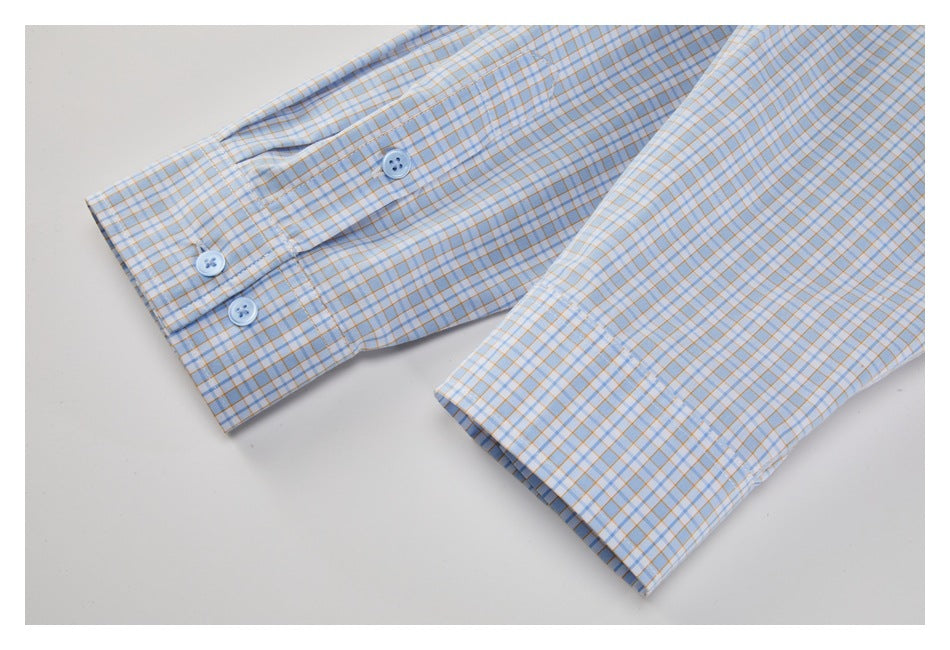 Close-up of two cuffs on a light blue shirt with a fine tan-and-blue grid and pale blue buttons.
