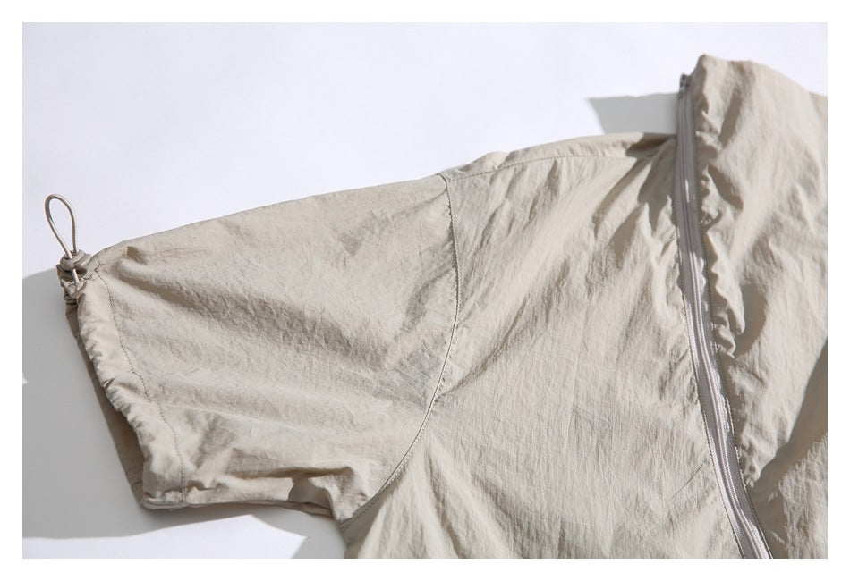Close-up of a beige jacket sleeve beside the diagonal front zipper.