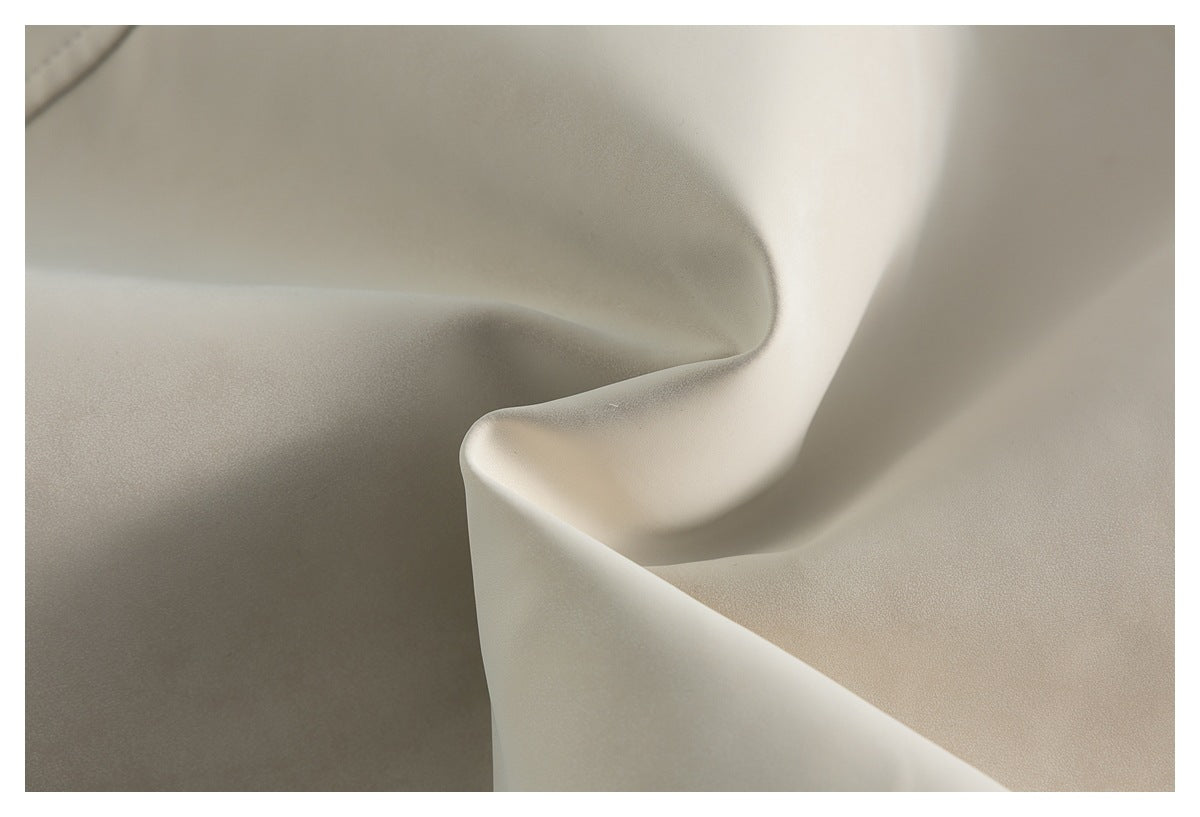 Close-up of smooth ivory-beige fabric draped into soft folds.
