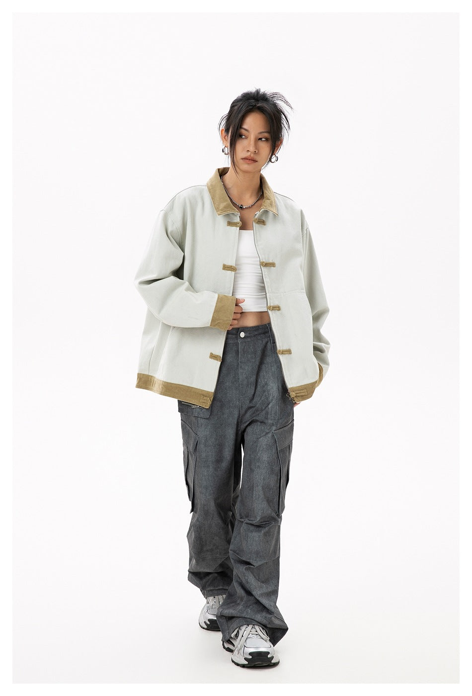 Full-length model wearing a pale gray oversized jacket with tan trim and toggle closures, styled with dark cargo pants.