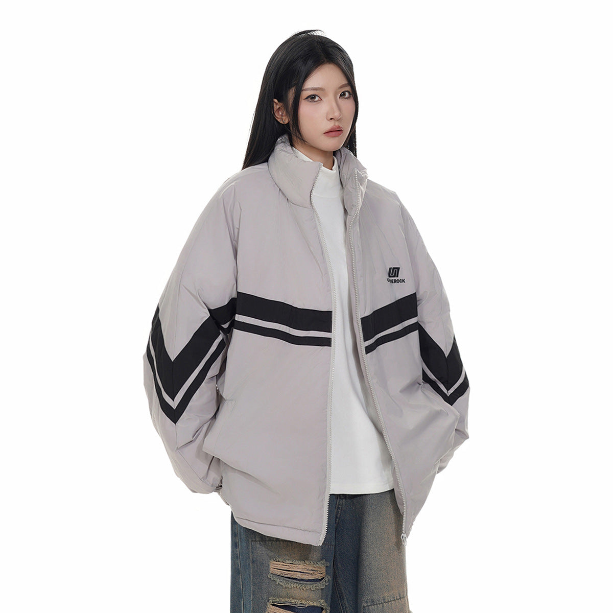 Model wearing a light gray oversized zip jacket with black chevron stripes, front three-quarter view.