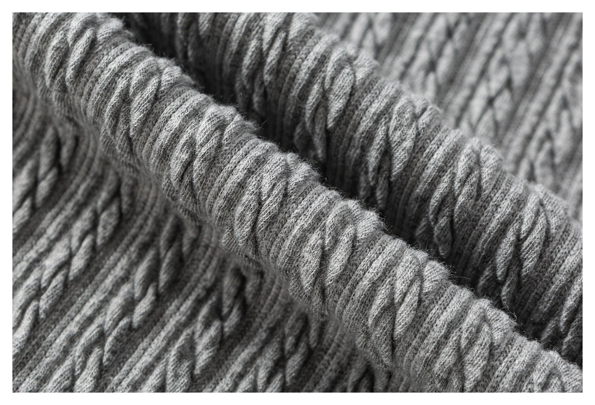 Extreme close-up of raised cable-knit stitches in gray fabric.