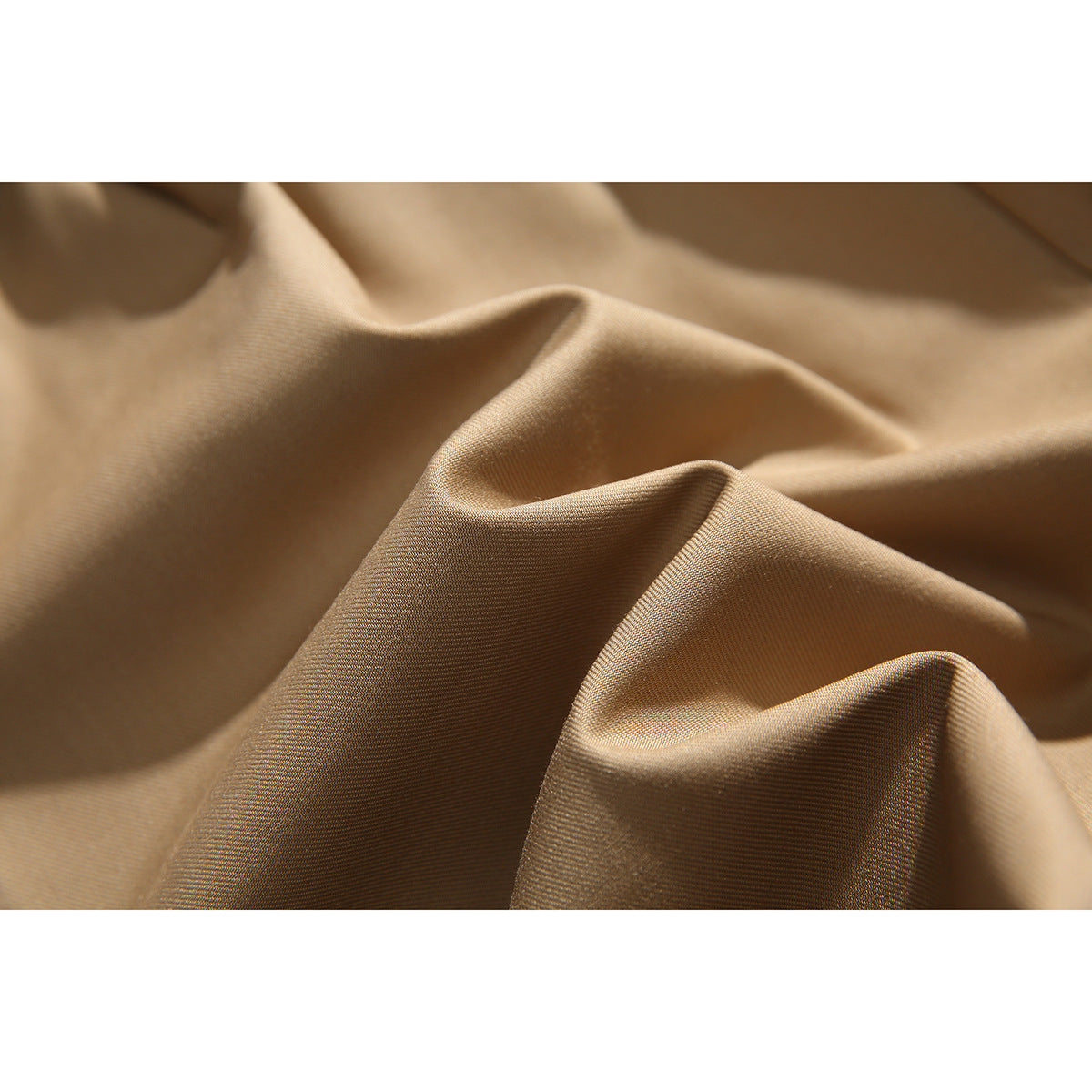 Extreme close-up of the tan shorts fabric, showing its fine woven texture and folds.