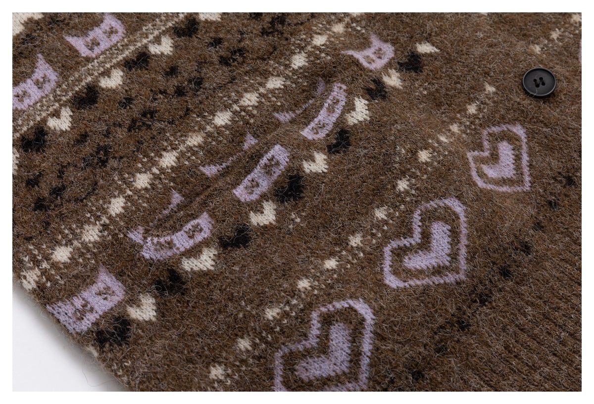 Close-up of brown cardigan knit with repeating cream and lavender motifs and a black button.