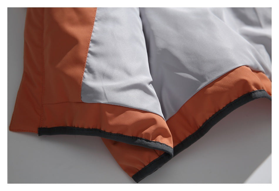 Close-up of a light gray jacket panel bordered by rust-orange fabric and black trim.