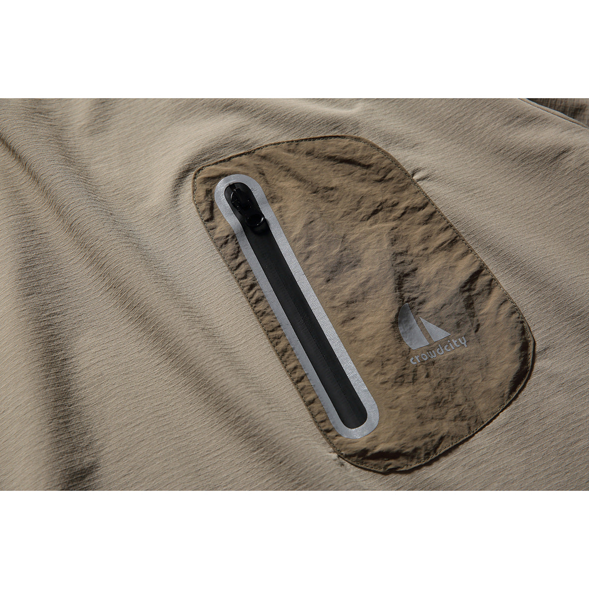 Close-up of the pullover's brown chest pocket with a vertical zipper and small logo.