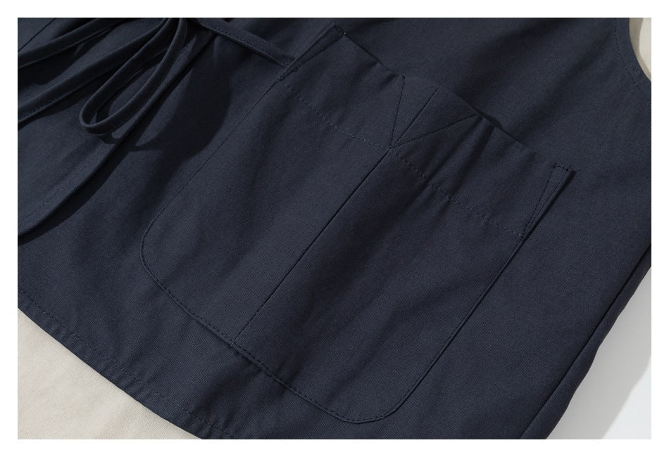 Close-up of a large patch pocket with stitched panel details on a dark navy garment.