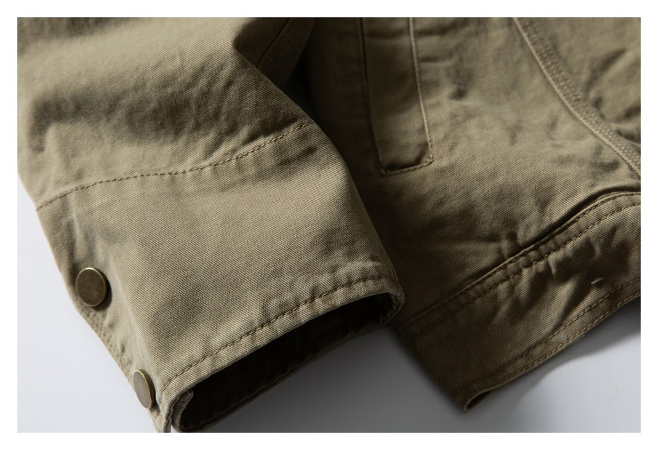 Close-up of an olive-khaki sleeve cuff with two round metal snaps and visible stitching.