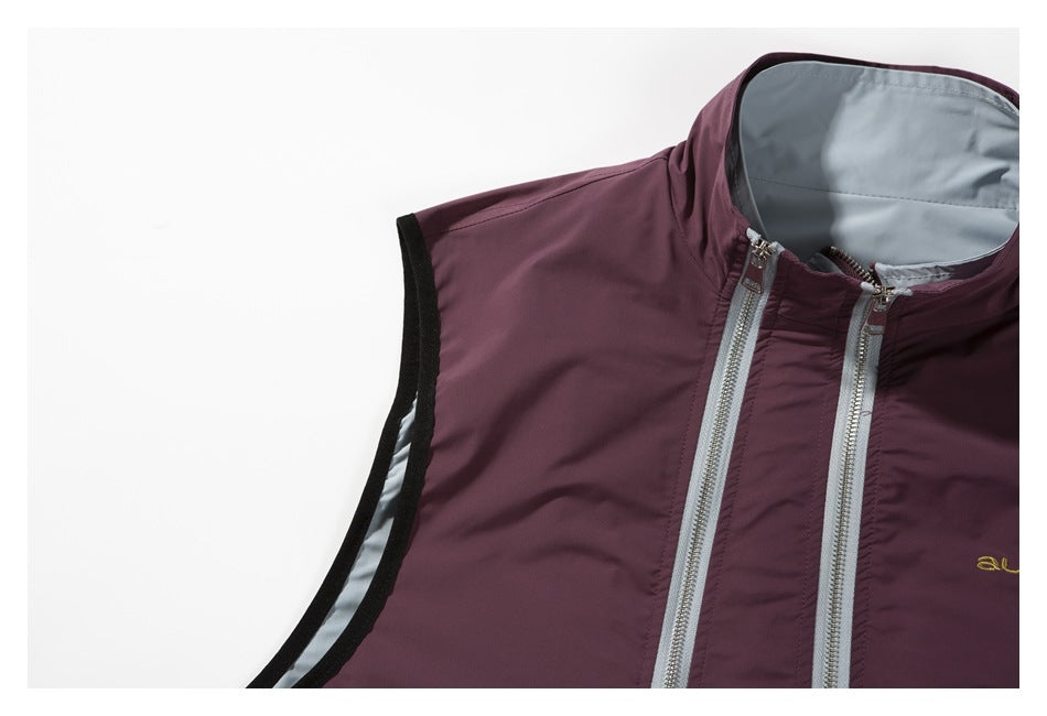Partial close view of the burgundy vest's shoulder, black-edged armhole, collar, and twin silver zippers.