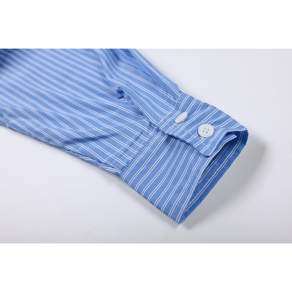 Close-up of the blue-and-white striped shirt cuff with two white buttons.