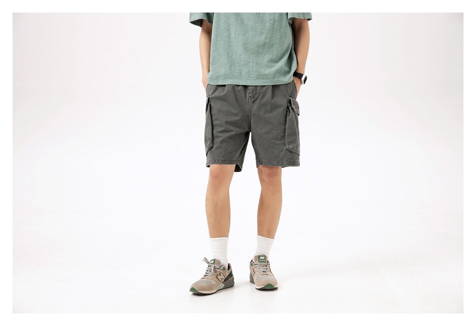 Front view of a model wearing charcoal gray cargo shorts with large flap pockets on both sides.