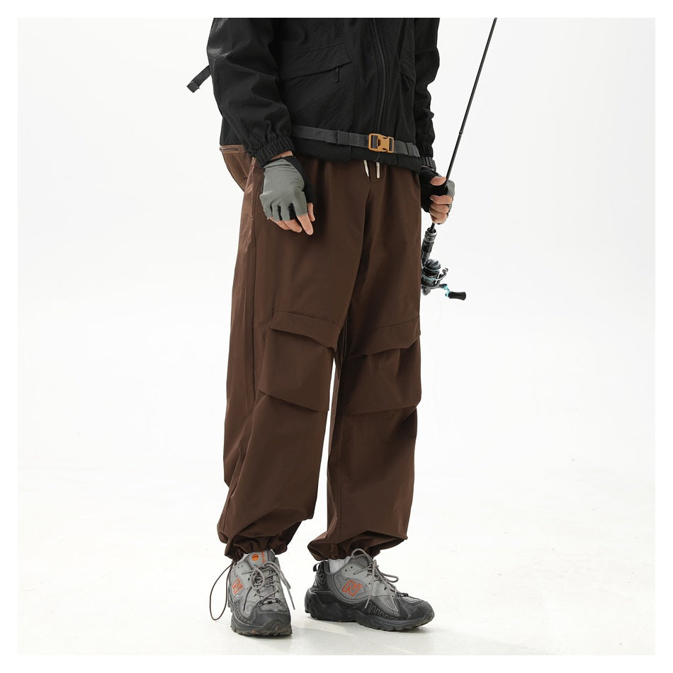 Model wearing loose dark brown cargo pants with layered thigh pockets, shown from the front while fishing.