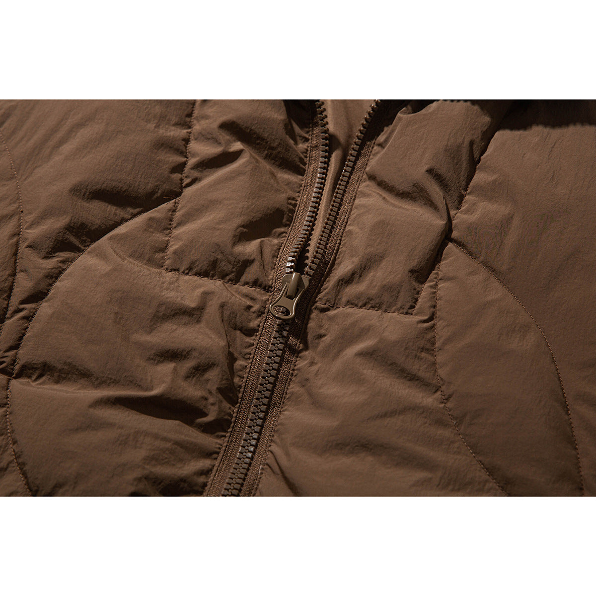 Close-up of the brown padded jacket's front zipper and stitched quilting.