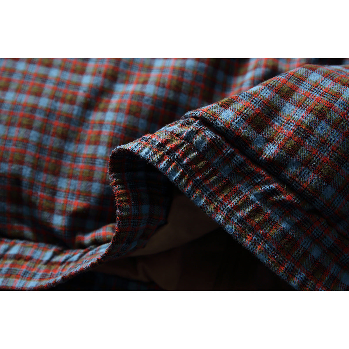 Close-up of the blue and rust plaid fabric and folded sleeve cuff area.
