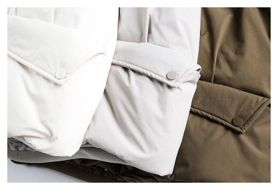 Close view of ivory, light gray, and olive garments with snap-button cuff tabs.