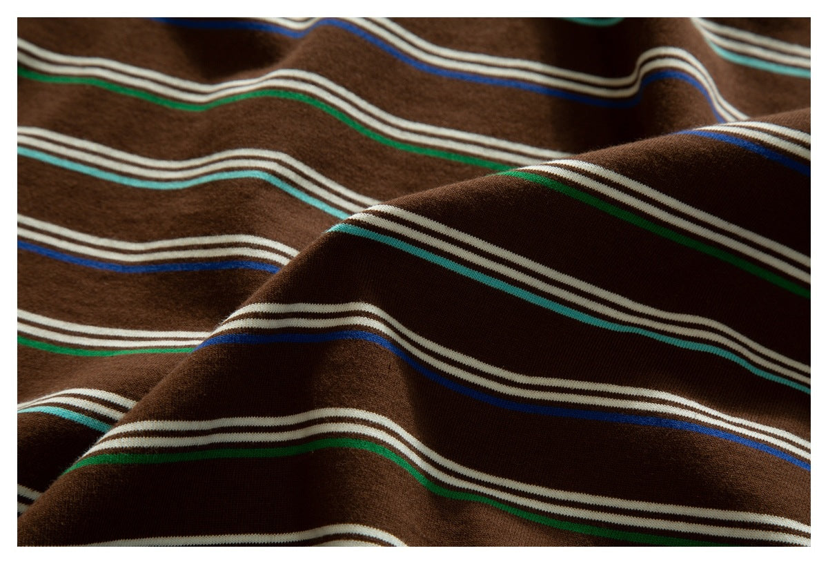 Close-up of draped brown garment fabric with horizontal cream, turquoise, green and blue stripes.