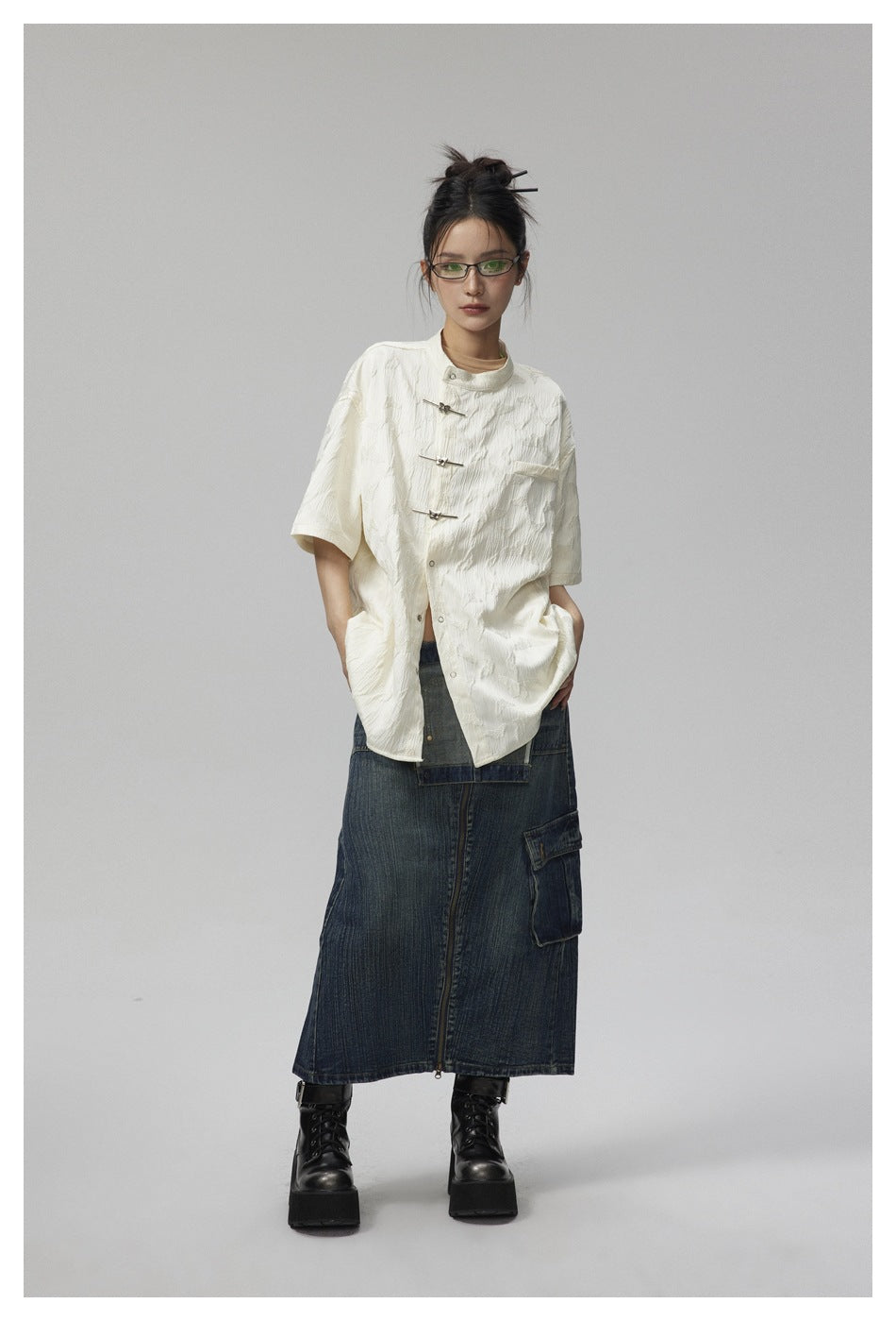 Front view of a model wearing an oversized ivory jacket with frog closures and a raised pattern.