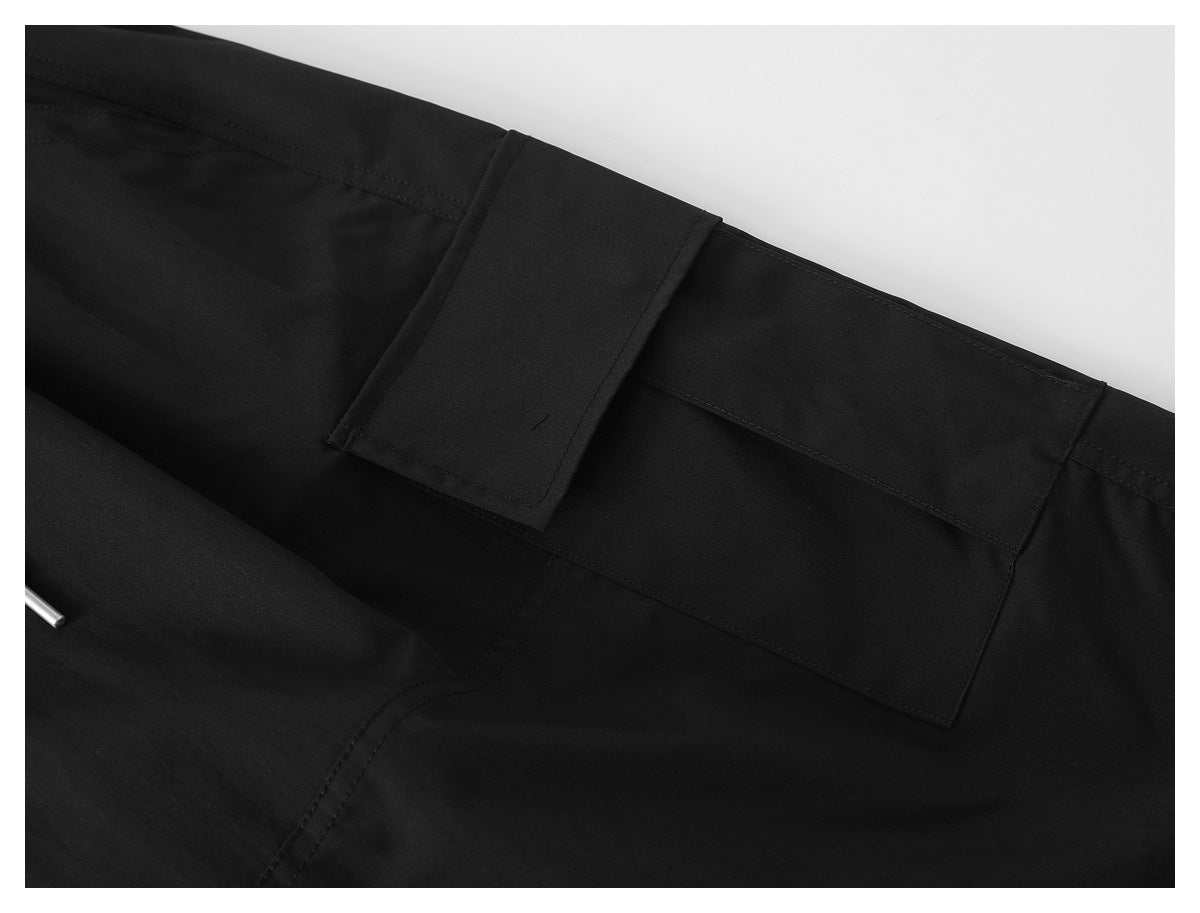 Close-up of a black pants leg showing a large flap cargo pocket and stitching.
