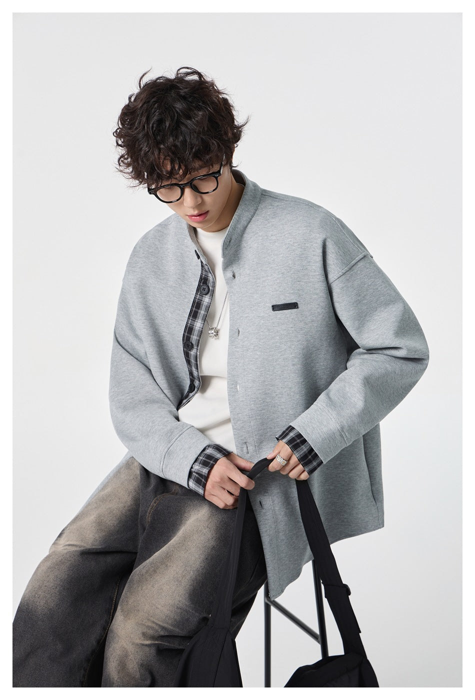 Model wearing a light gray stand-collar jacket with plaid inner placket and cuffs over a white top.