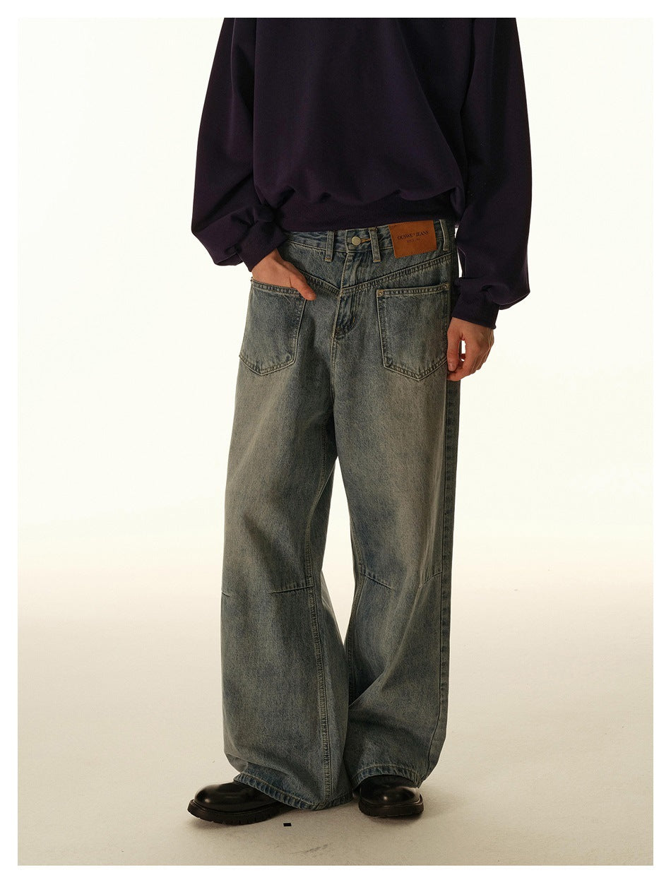 Person wearing faded blue wide-leg jeans with a dark purple sweatshirt and black boots, cropped from the waist down