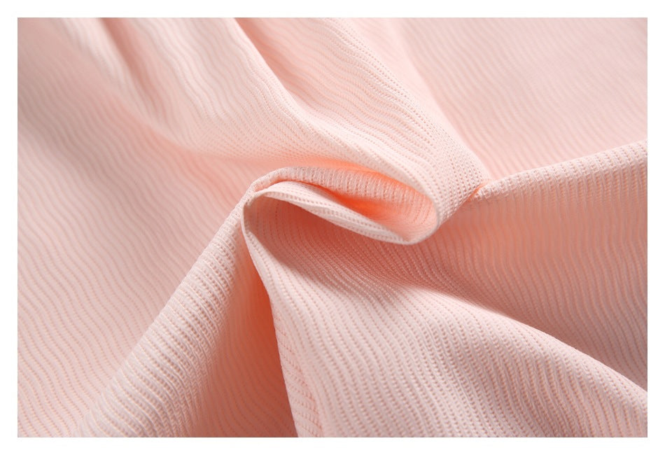 Close-up of pale pink ribbed fabric draped to show its texture and edge finish.