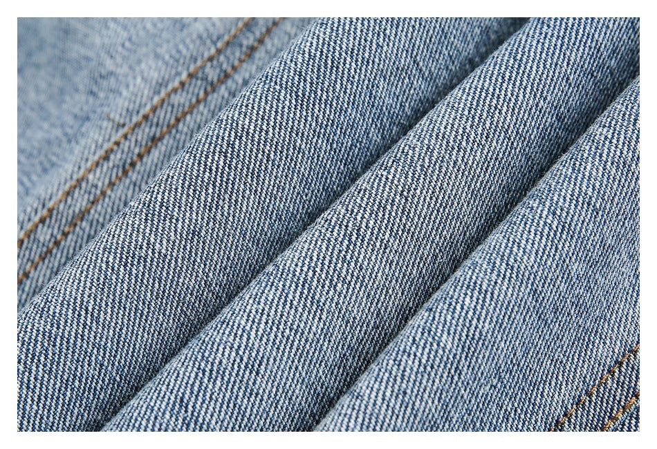 Macro view of blue denim fabric folded into ridges, showing its diagonal weave and texture.