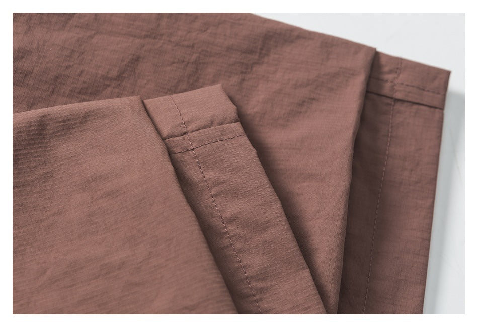 Close-up of folded mauve-brown garment panels with stitched edges and a hem.