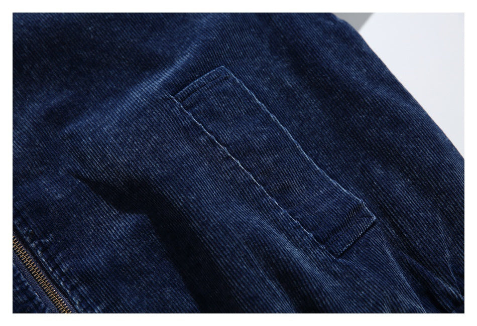 Close-up of a rectangular pocket stitched onto dark navy corduroy, with part of the brass zipper visible.