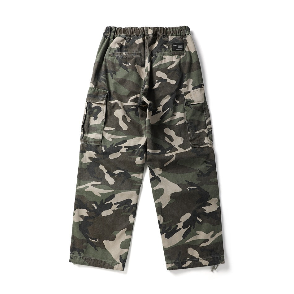 Back view of olive, tan, and black camouflage cargo pants with an elastic waist and side cargo pockets.