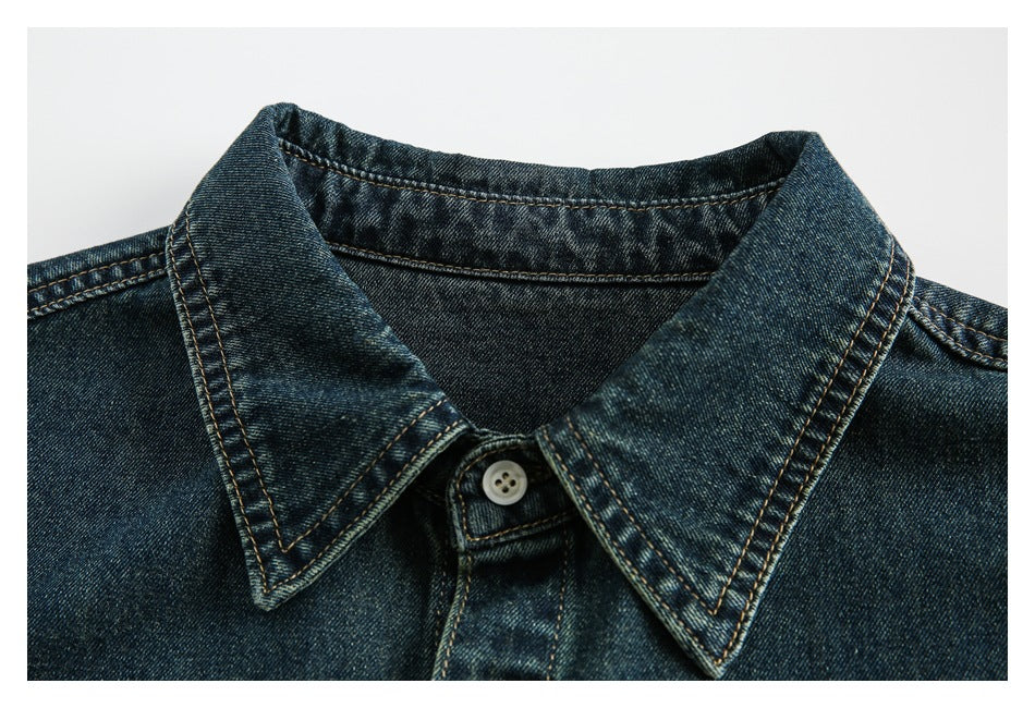 Close-up of a dark indigo denim shirt collar with tan contrast stitching and a white button.