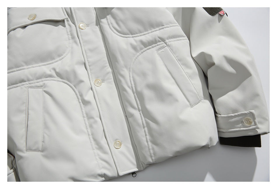 Close-up of the jacket's lower front pockets, button placket, sleeve cuff, and dark ribbed cuff trim.