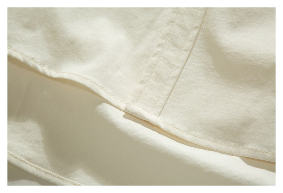 Close-up of an ivory garment hem and intersecting stitched seams.