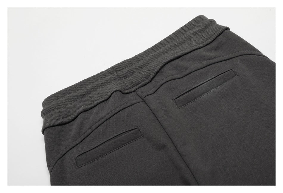 Close-up of the back waistband and two welt pockets on charcoal pants.