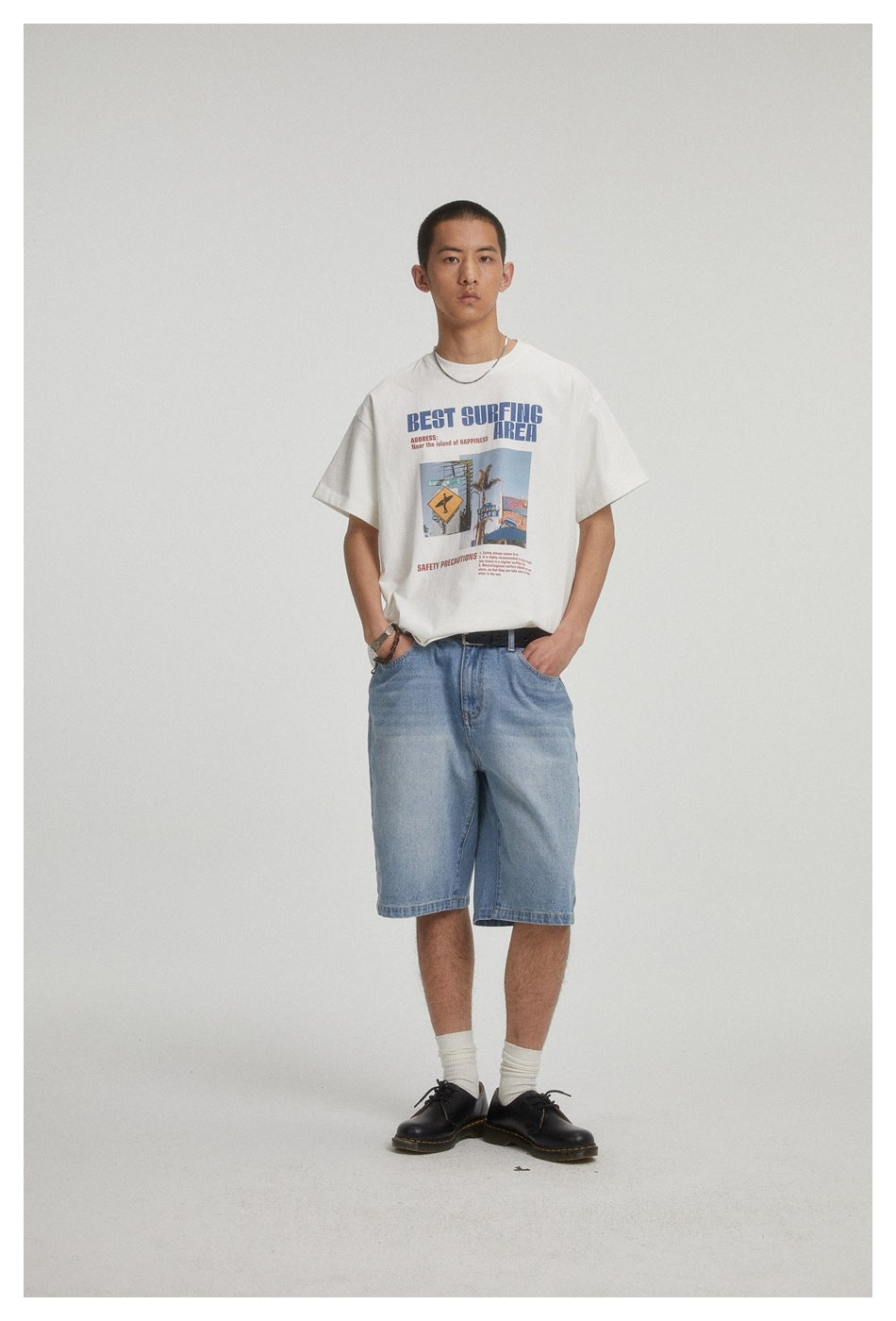 Front view of a model wearing a white graphic T-shirt with light blue denim shorts.