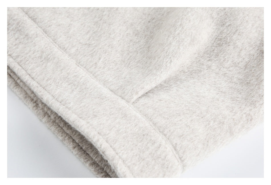 Close-up of a finished edge and seam on pale beige fuzzy coat fabric.