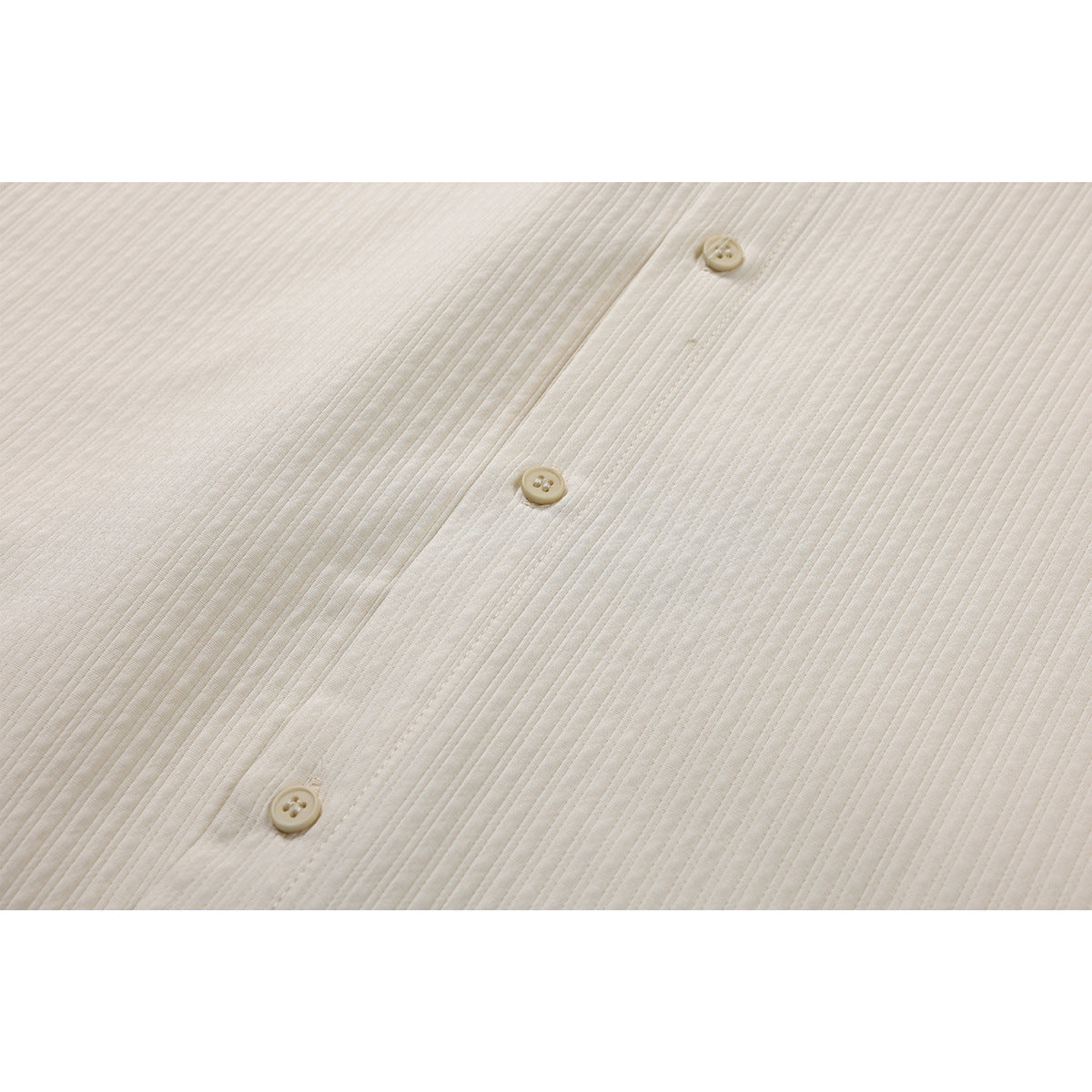 Close-up of three cream buttons on the ivory shirt's finely ribbed front.