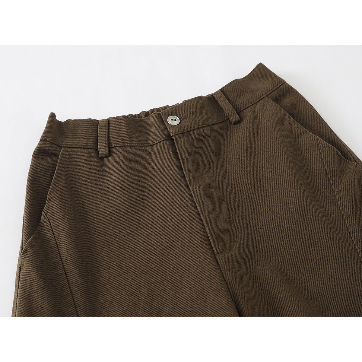Close-up of brown trousers showing the waistband, belt loops, button, fly and front pocket.