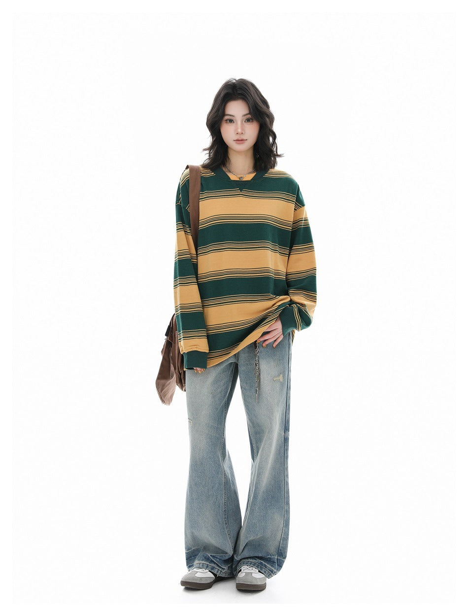 Full-length model wearing an oversized green and mustard striped long-sleeve shirt with loose light-wash jeans.