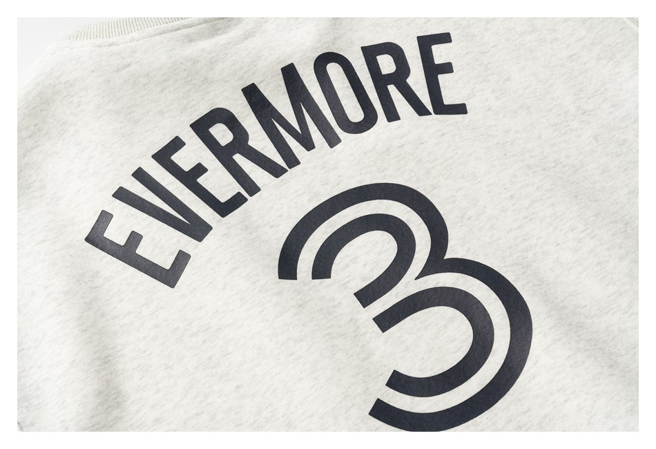 Close-up of an off-white sweatshirt with dark EVERMORE lettering and a large stylized 3 printed on it.
